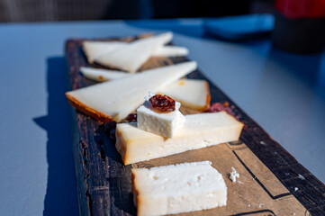 Tasting of Spanish cheeses made on Canary islands, goat cheese, smoked and triangles of manchego curado cheese on wooden plank