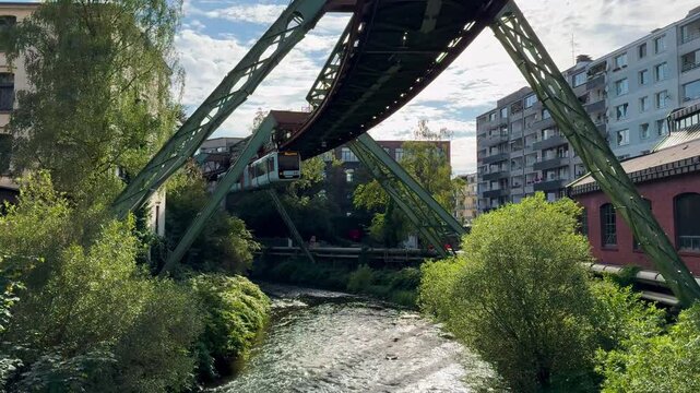 Train car moves on monorail suspended on overpass of Wuppertal Suspension Railway. Public transport metropolitan in Wuppertal, North Rhine Westphalia, Germany July 29, 2024. High quality 4k footage