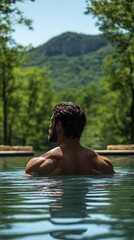 Fototapeta premium Muscular Man Relaxing In Outdoor Pool With Mountain View