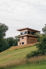 Fototapeta premium A contemporary wooden house elegantly situated on a hillside, embraced by lush greenery, offers breathtaking views of a tranquil landscape under cloudy skies