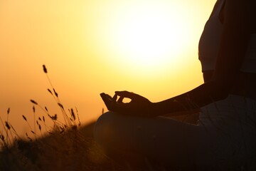 Silhouette of woman meditating outdoors at sunset, closeup. Space for text