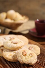 Tasty cashew cookies with powdered sugar on wooden board, closeup