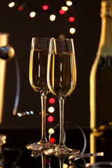 Champagne in glasses and bottle on black mirror surface