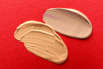 Samples of different foundations on red background, closeup