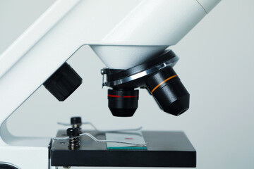 Science. Microscope with glass slide on light grey background, closeup
