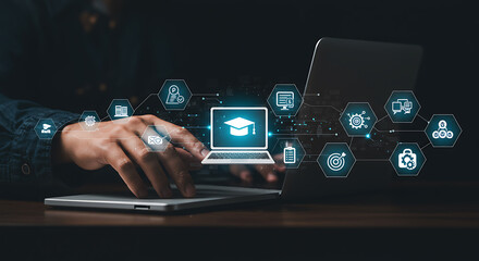 Businessperson Using Laptop With Online Education Icons Overlaid On Dark Background