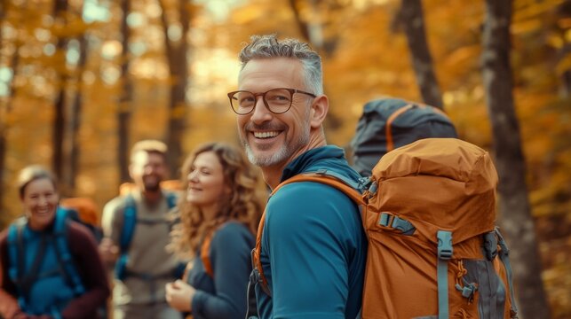 Smiling man with backpack hiking in autumn woods with friends. - Powered by Adobe