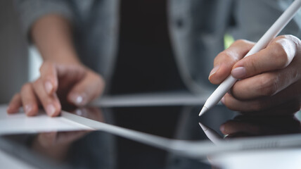Close up, woman hand using stylus pen on digital tablet on office table. Graphic designer working...