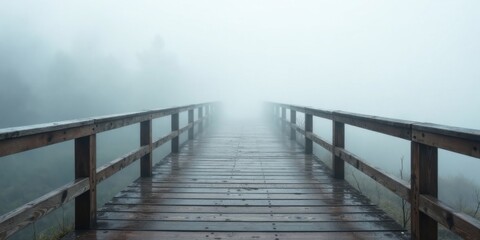 Naklejka premium Wooden walkway extending into a misty landscape, a path shrouded in fog, leading to an unseen destination.