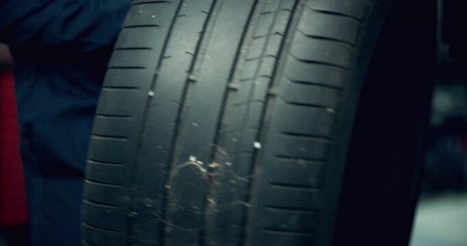 Hands, mechanic and change tire on car for repair service, auto maintenance or fix in professional garage. Man, workshop or remove wheel of vehicle for inspection, check alignment or transport safety