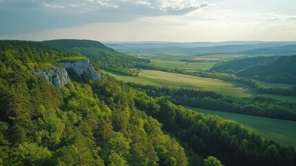 Obraz premium Panoramic vista of lush green hills and valleys under a cloudy sky