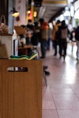 Wooden sign post adorned by stuffed toy snake sets jubilant mood for bokeh background view of arcade bustling with holiday visitors dressed for cool weather.