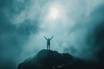 Silhouette of person celebrating victory on mountain peak in fog.