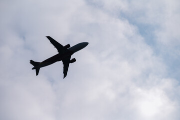 Silhouette of an Aircraft flying against the sky and clouds. Aircraft is a vehicle (such as an airplane or balloon) for traveling through the air.