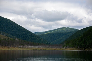Picturesque lake. Green hills are reflected in the calm water of the Zeya reservoir. Protected Russia.