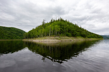 Picturesque lake. Green hills are reflected in the calm water of the Zeya reservoir. Protected Russia.