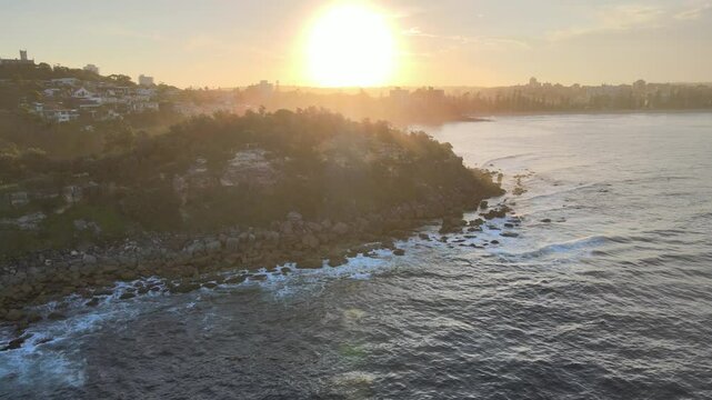 Drone video from shelly beach manly, moving to the right to reveal the sunset over manly and the beach