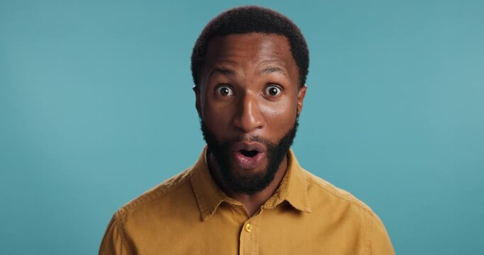 Smile, surprise and face of black man in studio for good news, announcement and notification. Promotion, wow and shocked with person on blue background for results, alert and mind blow emoji