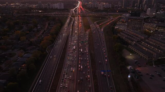 Heavy traffic on Highway 401 and 404 in Ontario at dusk, with city lights glowing
