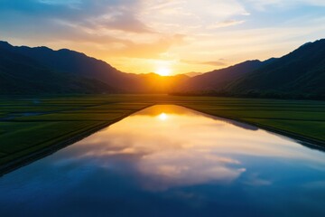 Obraz premium A breathtaking sunset over a serene lake surrounded by majestic mountains, reflecting warm hues and creating a tranquil atmosphere.