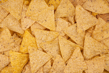 Close-up of yellow tortilla chips creating a textured background, perfect for food, snacks, or Mexican cuisine concepts.