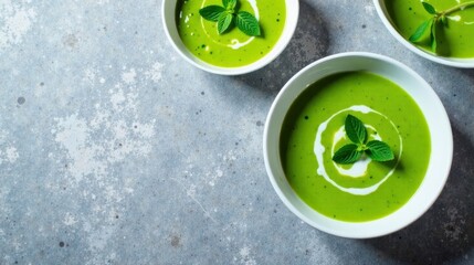 Creamy Green Pea Soup with Fresh Mint Garnish, Served in Elegant Bowls on a Textured Surface