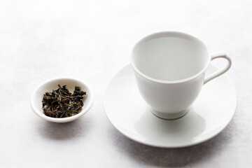 Cup of hot tea with tea leaf on white table background.