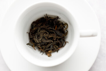 Cup of hot tea with tea leaf on white table background.