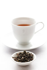Cup of hot tea with tea leaf on white table background.