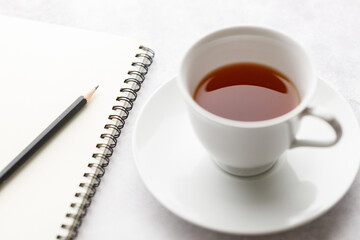 Cup of hot and notebook with pencil on white table background. Study time concept.