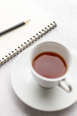 Cup of hot and notebook with pencil on white table background. Study time concept.