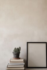 Cozy indoor setting featuring a blank poster frame on stacked books, a potted cactus, and a minimalist backdrop. Perfect for wall art mockups. Home decor template.