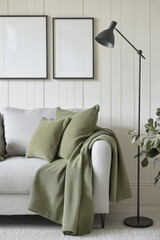 Cozy living room scene featuring modern gray sofa adorned with green pillows and blanket, stylish floor lamp, and empty wall art poster mockups for decor inspiration.