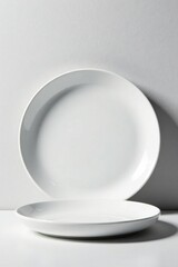 Fototapeta premium Two pristine white oval plates sit on a smooth surface against a bright backdrop, displaying elegant simplicity and minimalist design