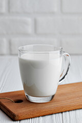 milk in glass cup on table with white brick wall on the background