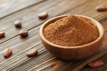 cocoa powder in bowl and raw cocoa beans on table