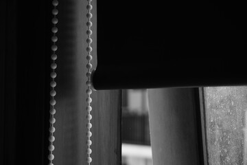 The window is open with roller blind curtains that are rolled up in black and white fashion