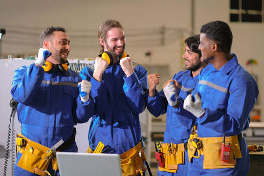 Group of mixed ethinity engineer team in blue suit show grateful of success work by fist hand in the air and smile. Win progressive congrate eacother in team.