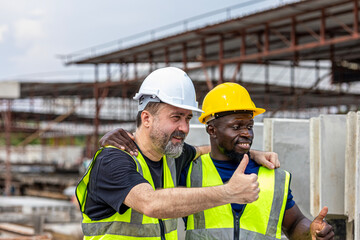 Two male engineers from different cultures and ages work together in a floor making factory. Senior supervisor discusses with his African engineer checking the concrete wall production system