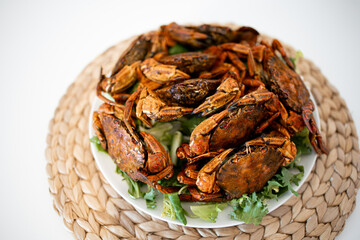 Delicious spicy whole roasted crabs on woven mat background