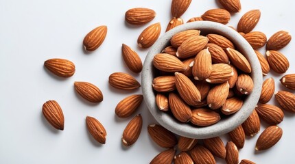 Almonds in a stone bowl scattered on a white background showcasing their natural texture and color for healthy eating concepts.
