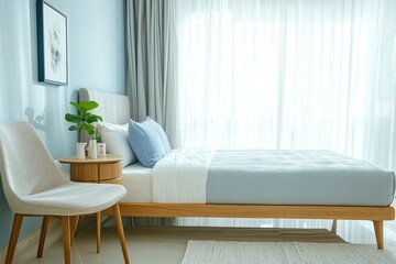 Fototapeta premium Modern bedroom with light blue and gray tones, beige bed frame, soft mattress, wooden side table, plant, and sheer curtains creating a cozy, serene atmosphere.