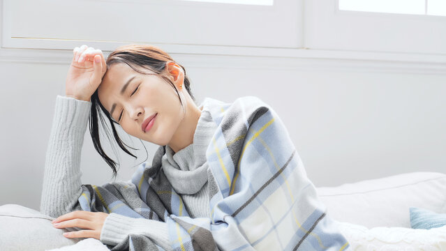 女性、発熱、疲労、風邪、かぜ、冬、日本人、インフルエンザ、寒い、寒暖差、咳き込む、冷え性、室内、リビングルーム、体調不良、疲れ、ダウン、ストール、防寒、エアコン、暖房、アレルギー、交感神経、自律神経、ストレス、困る、悩む、悩み、ブランケット、毛布、対策、休む、つらい、落ち込む、がっかり、頭痛、コロナ、ライノウイルス、RSウイルス、寒気、悪寒、溶連菌、冬風邪、倦怠感、寝込む、病気、休養、不安、バテる