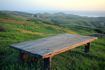 Rustic wooden table overlooking scenic coastal hills and wildflowers at sunset