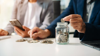 Fototapeta premium Hand putting mix coins and seed in clear bottle and business investment growth concept.