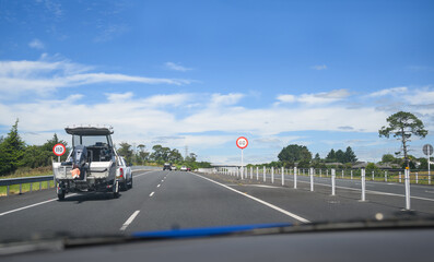 Car towing a boat on Waikato Expressway. 110 kmh road speed signs by the side of highway. New...