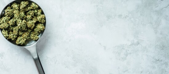 Metal scoop with cannabis buds on glass scale against a blank background for product display or marketing purposes.