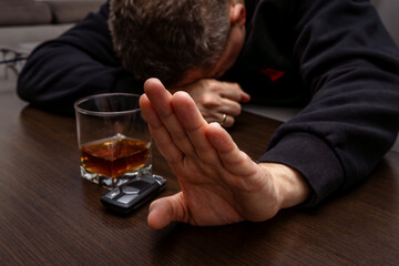 Drunk man lying on the table with a glass of alcohol, car keys on the counter, drunk car driver, drowning his sadness in a glass of whiskey