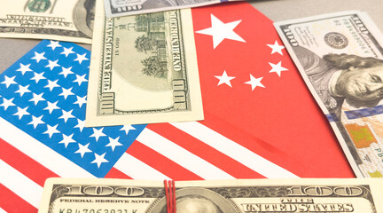 Us and china flags with currency symbolizing economic relations.
