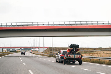 Car pulling trailer carrying ATV on road © AlexGo